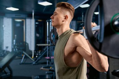 Sporcu halter kullanarak çömeliyor..