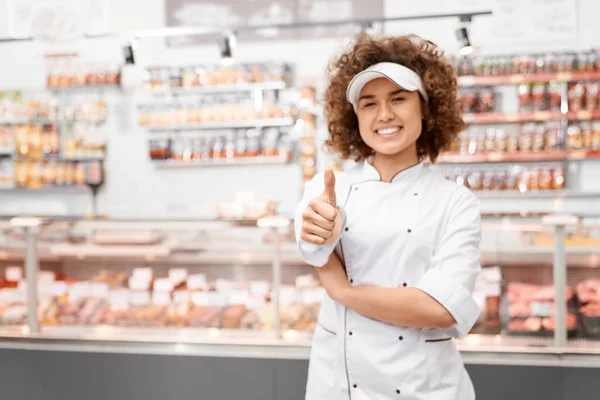 Shop worker showing thumb.