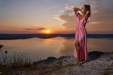 Uzun elbiseli, taş üstünde duran bir kız..