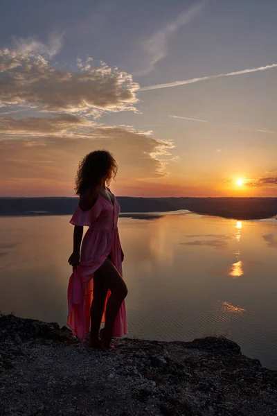 Model pozowanie w sukience na tle zachodu słońca w pobliżu jeziora. — Zdjęcie stockowe