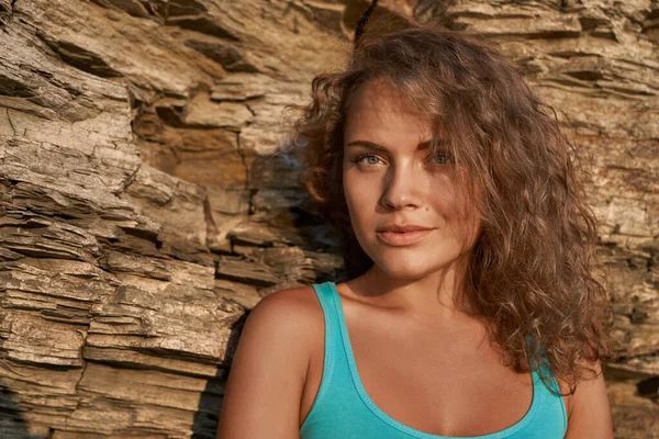 Chica elegante con el pelo rizado en el fondo de la roca . — Foto de Stock