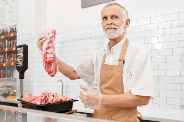 Carnicero macho demostrando carne en supermercado . — Foto de Stock