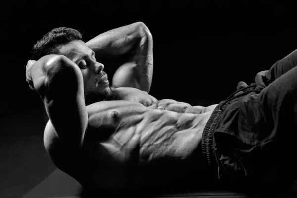 Shirtless man träning abs på golvet, monokrom. — Stockfoto