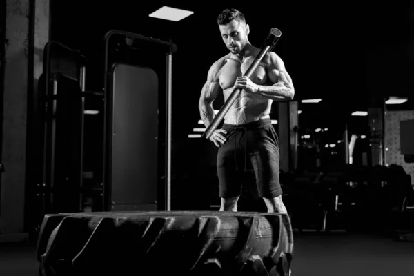 Muskelkräftiger Bodybuilder hält Vorschlaghammer auf Schulter. — Stockfoto