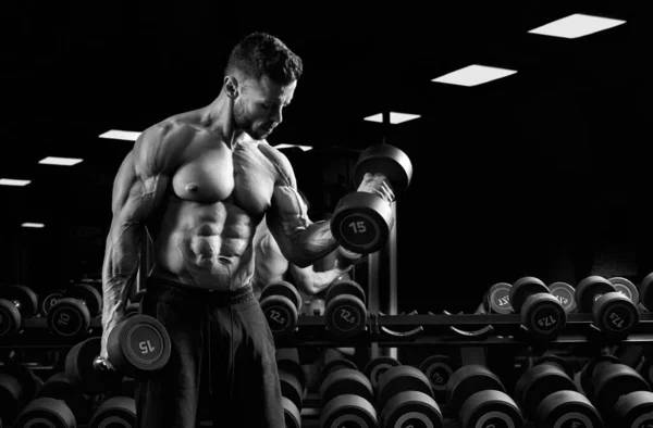 Black and white portrait of sportsman training biceps. — Stock Photo, Image