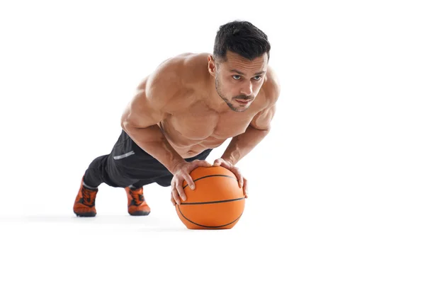 Bytový bodubuilder bez košile dělá kliky pomocí basketbalu. — Stock fotografie