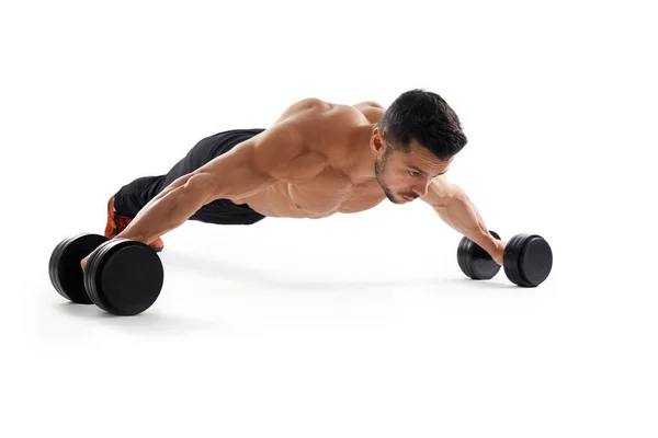 Bodybuilder doet brede push-ups met behulp van halters. — Stockfoto