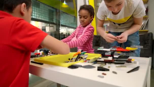 Діти використовують будівельний набір для створення іграшок . — стокове відео