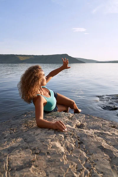 Meisje liggend op steen op de achtergrond van bergen en water. — Stockfoto