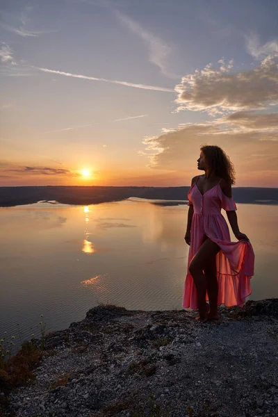 Model im langen Kleid posiert vor dem Hintergrund des Sonnenuntergangs. — Stockfoto