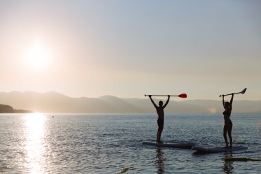 Sup sörf ve okyanus, elinde kürek ile güzel çift silüeti. Kavramı yaşam tarzı, spor, aşk