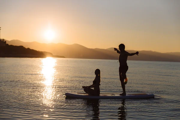 Yoga poz ve okyanus, sup internet üzerinde oturan kız çocuk silüeti. Kavramı yaşam tarzı, spor, aşk
