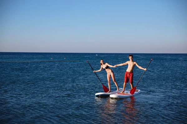 Felicidad chico y chica en sup surf natación en el océano. Concepto estilo de vida, deporte, amor — Foto de Stock