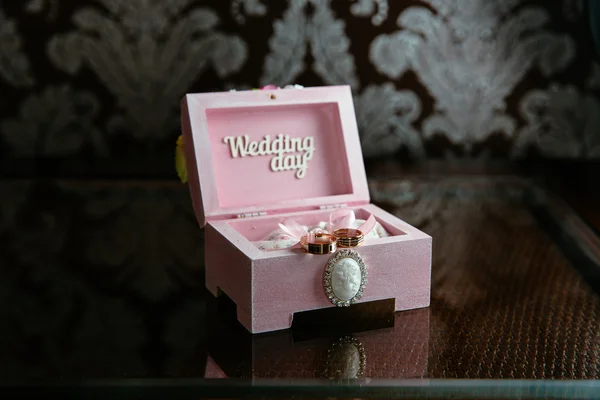 Deux anneaux dans une boîte avec inscription du jour du mariage sur la table noire. Notion de mariage — Photo