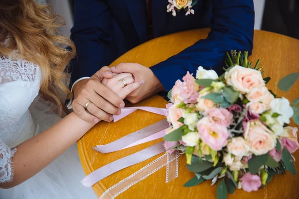 Noiva e noivos mãos com anéis de casamento na mesa marrom — Fotografia de Stock