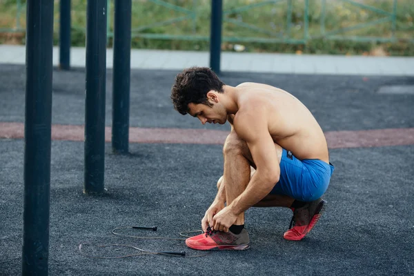 Muskulös man knyta skor innan träning på crossfit marken, närbild. Sport-konceptet — Stockfoto