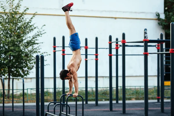 Hombre musculoso en el campo de deportes haciendo flexiones al revés como parte del entrenamiento. Concepto deportivo —  Fotos de Stock