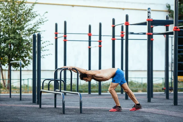 Hombre muscular calentando antes del ejercicio en el terreno crossfit haciendo flexiones como parte del entrenamiento. Concepto deportivo — Foto de Stock
