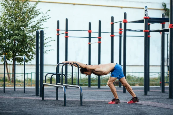 Hombre muscular calentando antes del ejercicio en el terreno crossfit haciendo flexiones como parte del entrenamiento. Concepto deportivo —  Fotos de Stock