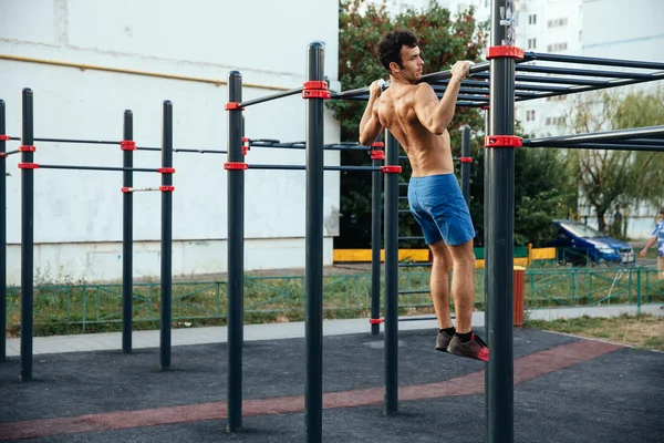 Muscular man warming up before exercise at crossfit ground doing push ups as part of training. Sport concept