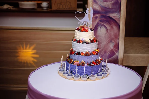 Солодкий багаторівневий весільний торт, прикрашений фруктами. Чорниця, полуниця, малина. Цукерки внизу — стокове фото