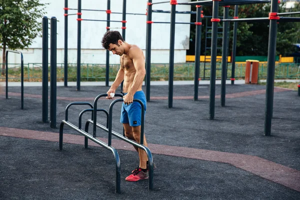 Hombre muscular calentando antes del ejercicio en el terreno crossfit haciendo flexiones como parte del entrenamiento. Concepto deportivo — Foto de Stock