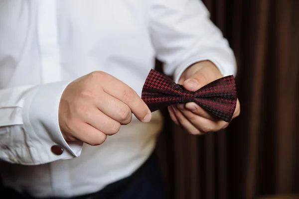 Accesorios de boda. Corbata de lazo marrón en las manos del novio —  Fotos de Stock