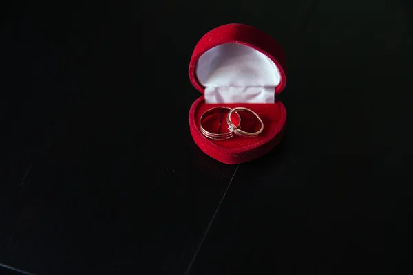 Anillos de boda de oro sobre fondo oscuro en caja roja — Foto de Stock