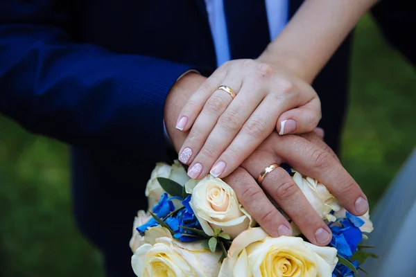 Sposa e sposi mani con fedi nuziali su mazzo di fiori — Foto Stock