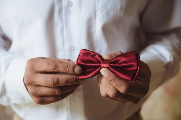 Accessori da sposa. Papillon rosso nelle mani dello sposo — Foto Stock