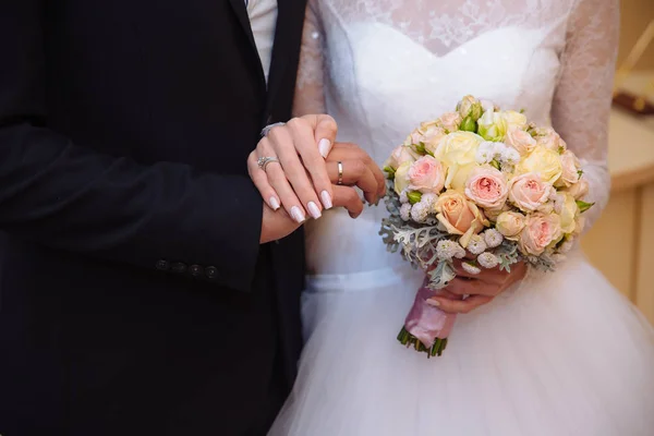 Руки жениха и невесты с обручальными кольцами на коричневом столе — стоковое фото
