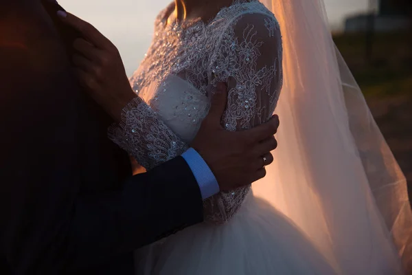 Sposo e sposa si tengono per mano al tramonto, giorno del matrimonio. Concetto di famiglia dell'amore — Foto Stock