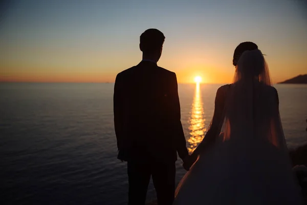 Sposo e sposa si tengono per mano al tramonto, giorno del matrimonio. Concetto di famiglia dell'amore — Foto Stock