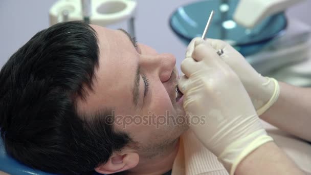 Dentista feminino fazendo procedimentos para paciente do sexo masculino na clínica, close-up — Vídeo de Stock