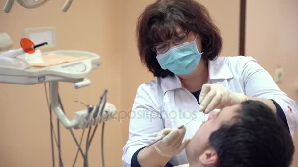 Dentista feminino fazendo procedimentos para paciente do sexo masculino na clínica, close-up — Vídeo de Stock