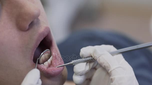 Médica dentista jovem fazendo procedimentos com paciente do sexo masculino, colocando luvas de proteção. Conceito de vida saudável. Fechar cena — Vídeo de Stock