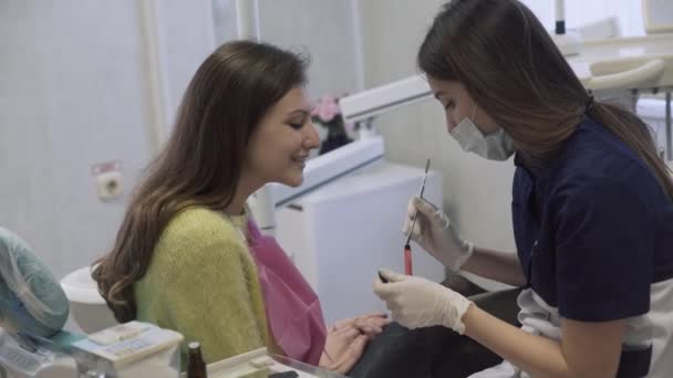 El dentista hace procedimientos y trata los dientes de una hermosa paciente en la clínica dental. Concepto de vida saludable — Vídeos de Stock