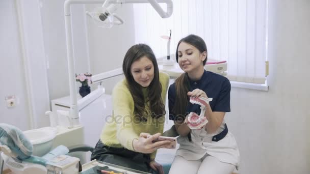 Dvě krásné dívky zubař a pacient dělá selfie na smartphone s úsměvem a smát na zubní klinice po procedurách. Happy klientů. Koncept zdravého života — Stock video