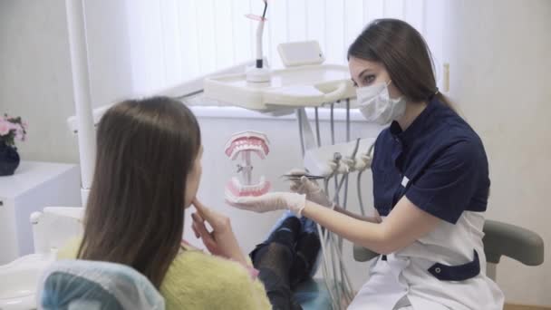 El dentista hace procedimientos y trata los dientes de una hermosa paciente en la clínica dental. Concepto de vida saludable — Vídeo de stock