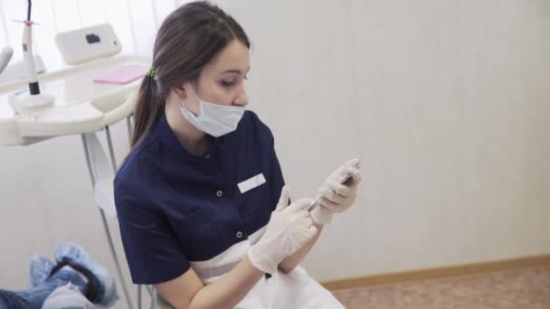 Mulher bonita dentista mensagens de texto ou bate-papo no smartphone em luvas estéreis e máscara médica — Vídeo de Stock
