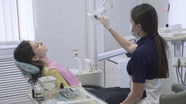 Prachtige vrouwelijke tandarts bereidt de patiënt voor de procedures in de tandheelkundige kliniek. Concept van het heatlhy leven. — Stockvideo