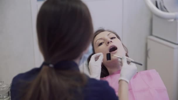 Dentist makes procedures and treat teeth for a beautiful patient woman in dental clinic. Concept of healthy life — Stock Video