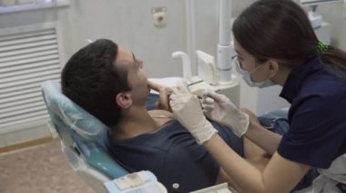 Erkek hasta yordamlarla yapma, koruyucu eldiven koyarak genç kadın dişçi doktor. Sağlıklı yaşam kavramı