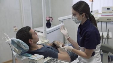 Dişçi genç kadın erkek hastaya diş ofisinde yordamlar yapma. Sağlıklı yaşam kavramı