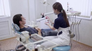 Erkek hasta yordamlarla yapma, koruyucu eldiven koyarak genç kadın dişçi doktor. Sağlıklı yaşam kavramı