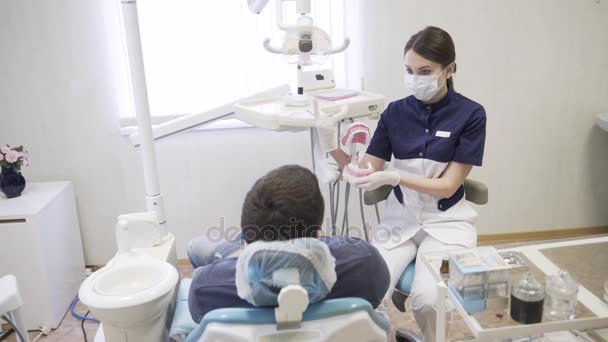 牙医程序向男性患者在牙科诊所的年轻女人。健康生活概念 — 图库视频影像