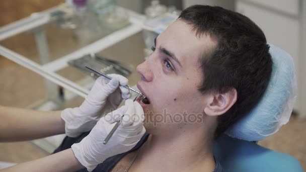 Junge Zahnärztin, die mit männlichen Patienten Eingriffe durchführt und Schutzhandschuhe anzieht. Konzept des gesunden Lebens — Stockvideo
