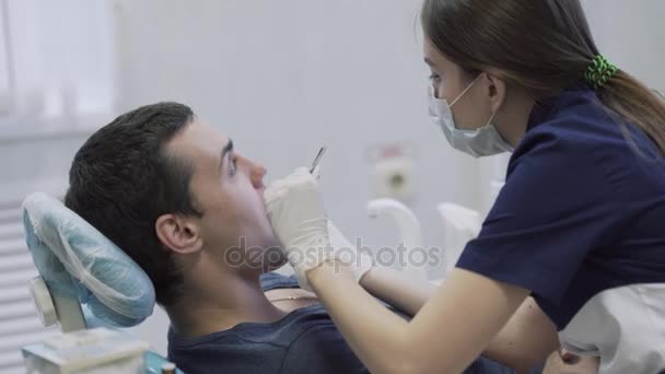 Giovane dentista ragazza che fa le procedure con i denti paziente maschile. Il dottore cura i denti. Concetto di vita sana — Video Stock