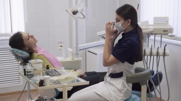 Bela dentista feminina prepara o paciente para os procedimentos na clínica odontológica. Conceito de vida quente . — Vídeo de Stock