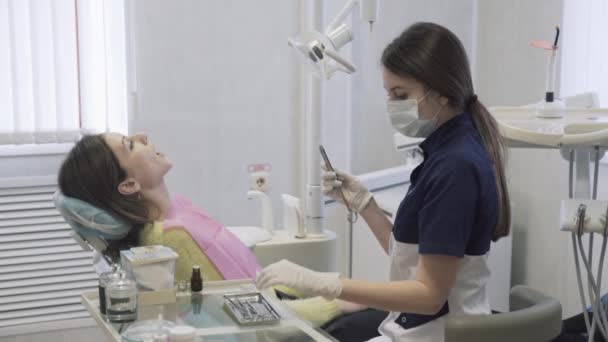 Bela dentista feminina prepara o paciente para os procedimentos na clínica odontológica. Conceito de vida quente . — Vídeo de Stock